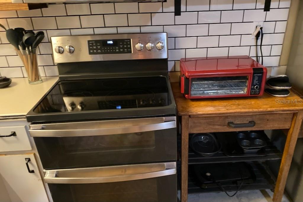 A kitchen features a stainless steel double oven range next to a red toaster oven — 2107 GROVE VALLEY AVENUE, PALM HARBOR, FL