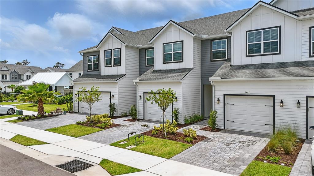 A row of modern townhouses features white siding, gray roofs, and paved driveways — 1462 BROOKDALE COURT, OVIEDO, FL