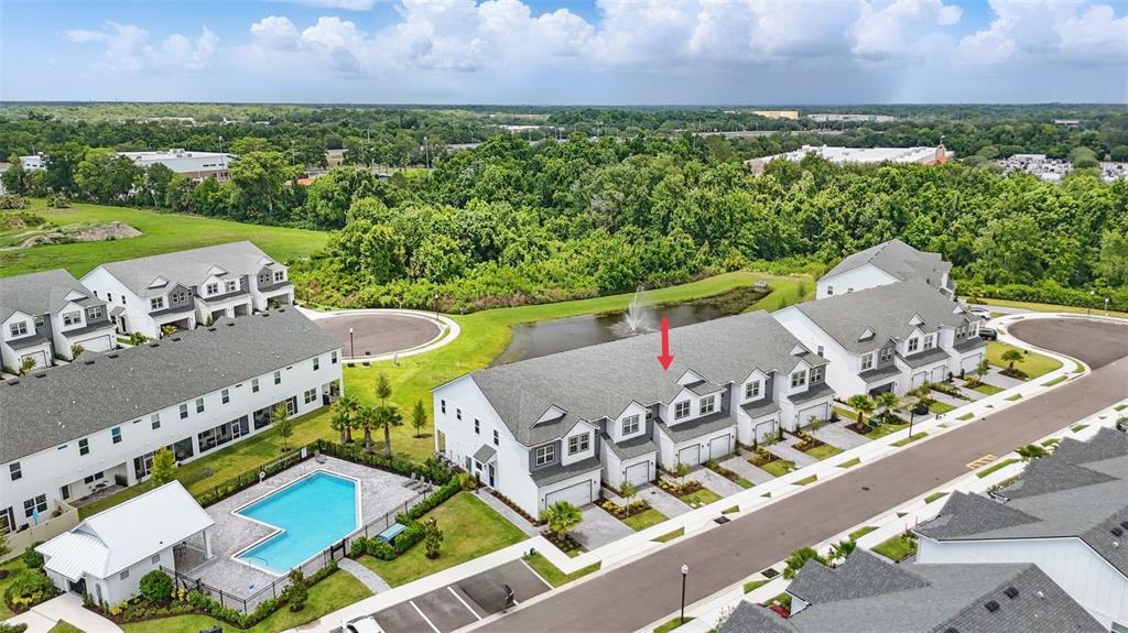 An aerial view shows a row of townhomes with a community pool and pond — 1462 BROOKDALE COURT, OVIEDO, FL