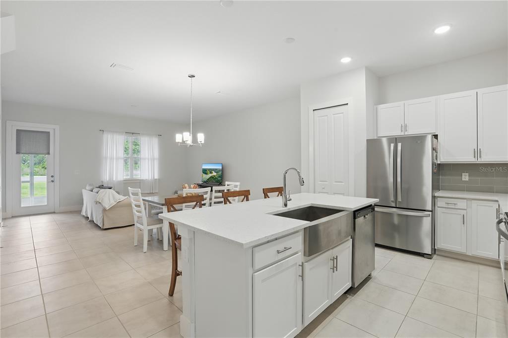 A kitchen with white cabinets and a farmhouse sink overlooks an open-concept dining area — 1462 BROOKDALE COURT, OVIEDO, FL