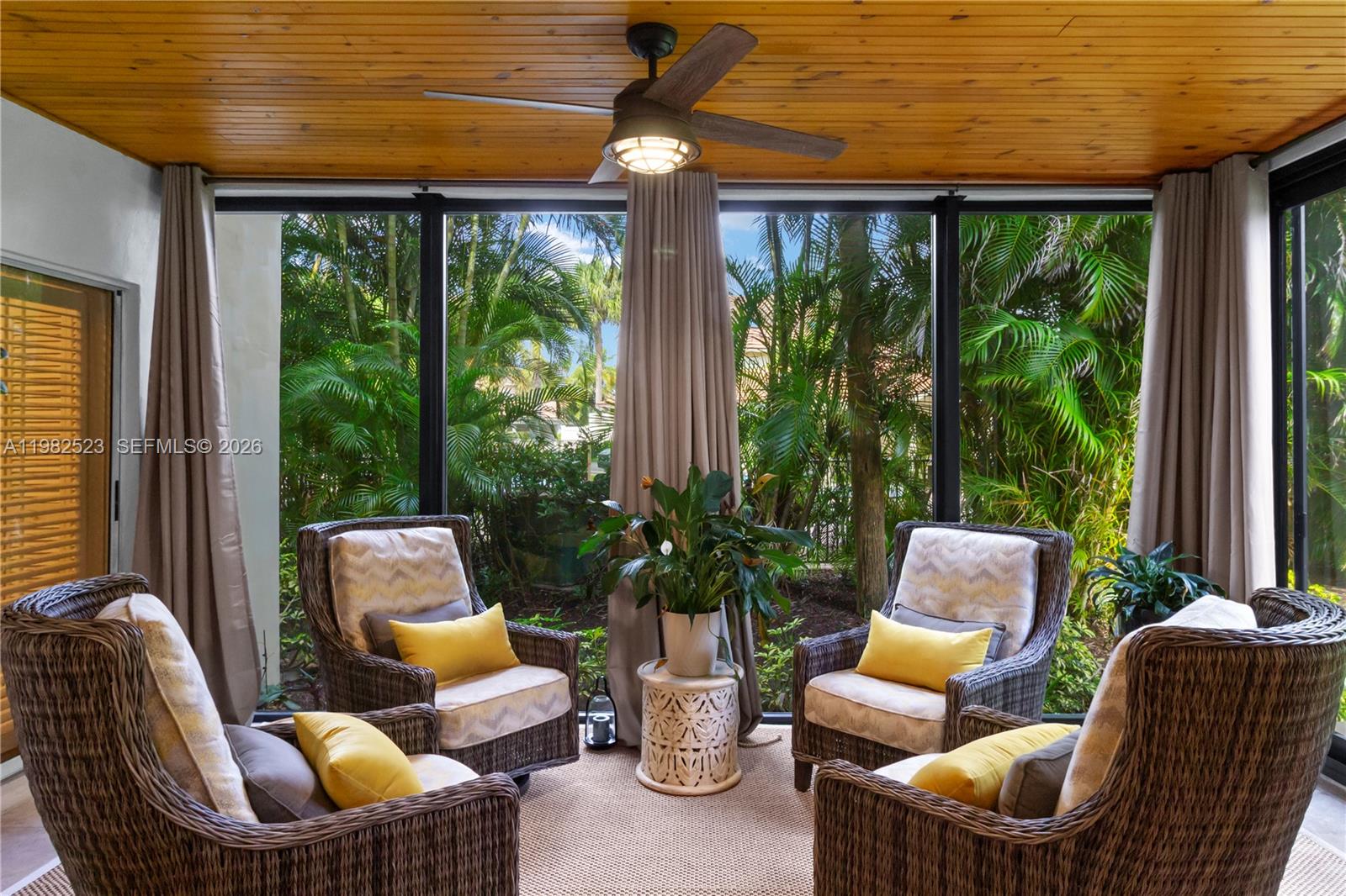A screened-in porch features wicker armchairs, a wooden ceiling, and views of tropical foliage — 4161 S Us Highway 1 # H1, Jupiter FL 33477, JUPITER, FL