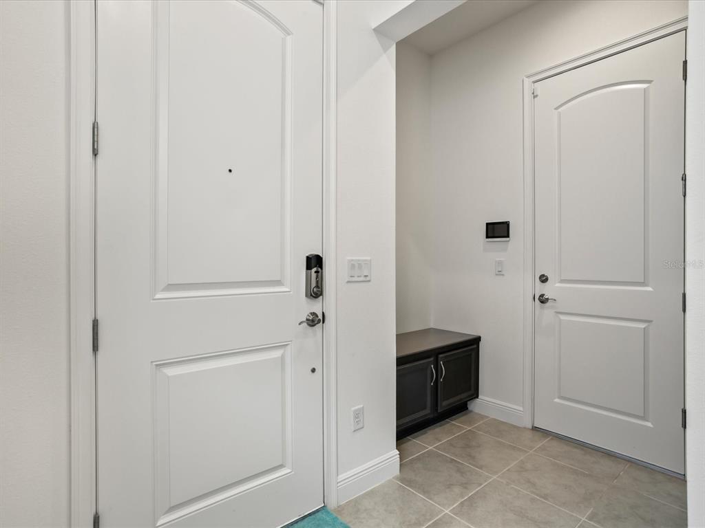 An entryway features two white doors, tile flooring, and a small dark storage cabinet — 13262 WINTERTON LANE, ORLANDO, FL