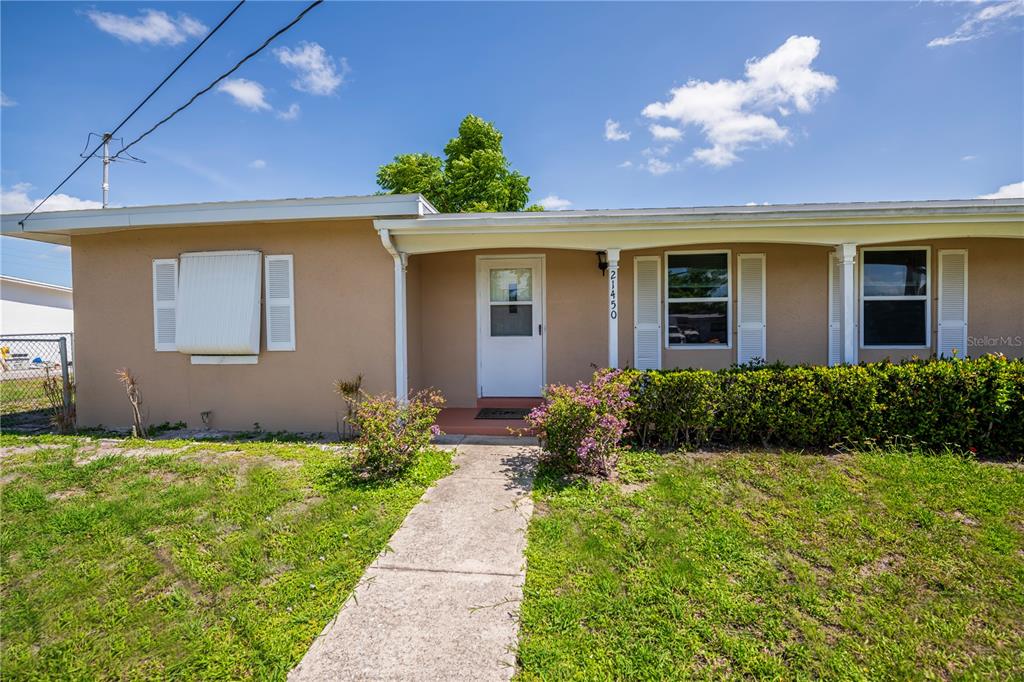 A single-story house with a tan exterior, white trim, and a concrete walkway — 21450 OLEAN BOULEVARD, PORT CHARLOTTE, FL