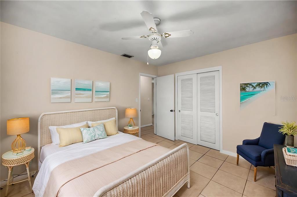 A bedroom features a bed with a wicker frame, a ceiling fan, and a blue chair — 21450 OLEAN BOULEVARD, PORT CHARLOTTE, FL