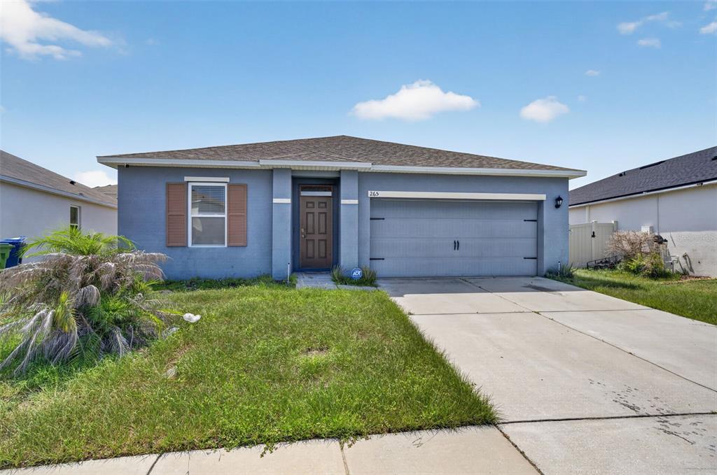 A single-story blue house with a two-car garage and a front lawn — 265 MEADOWBROOK BOULEVARD, WINTER HAVEN, FL
