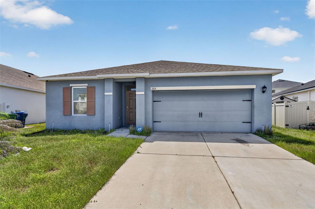 A single-story house with a blue stucco exterior, a two-car garage, and a concrete driveway — 265 MEADOWBROOK BOULEVARD, WINTER HAVEN, FL