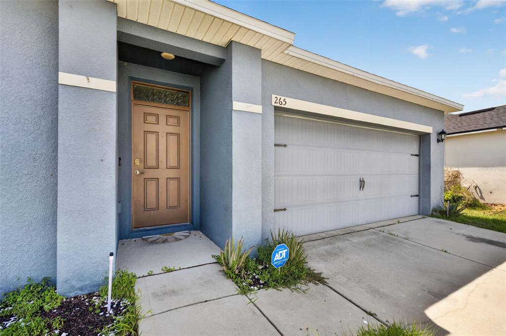 The exterior of a blue house features a brown front door and a two-car garage — 265 MEADOWBROOK BOULEVARD, WINTER HAVEN, FL