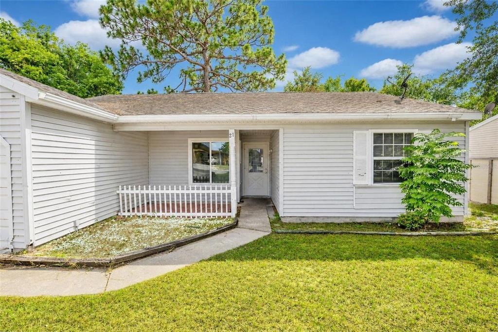 A single-story house with light gray siding, a small front porch, and a concrete walkway — 21 SPRING LOOP CIRCLE, OCALA, FL
