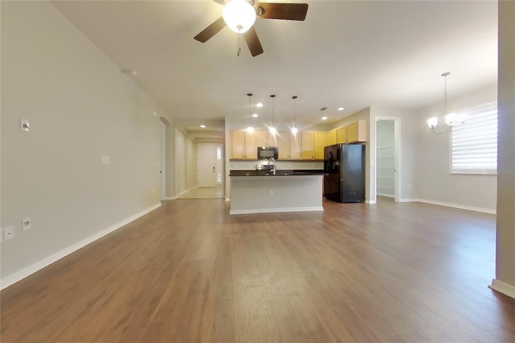 An open-concept kitchen and living area featuring wood-look flooring, light cabinetry, and a center island — 1255 MERION DRIVE, MOUNT DORA, FL