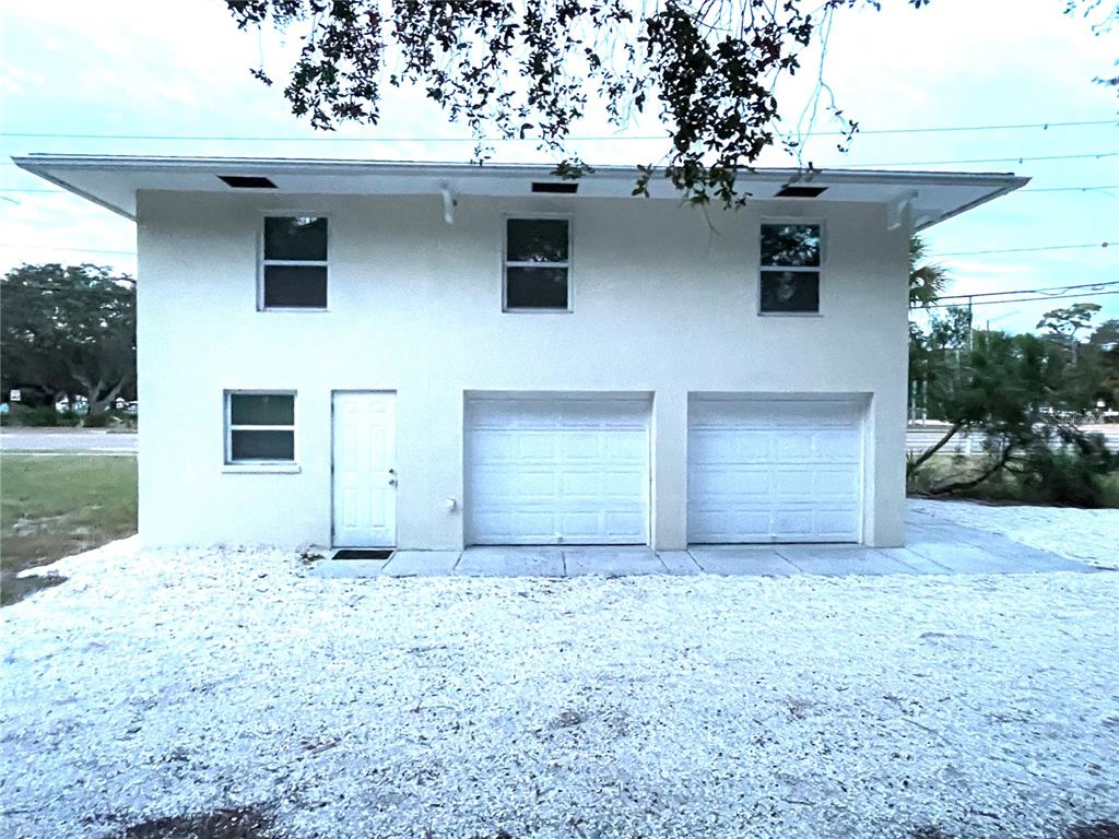 A two-story building features two garage doors, a side entry door, and three upper-level windows — 5370 71ST STREET N, ST PETERSBURG, FL