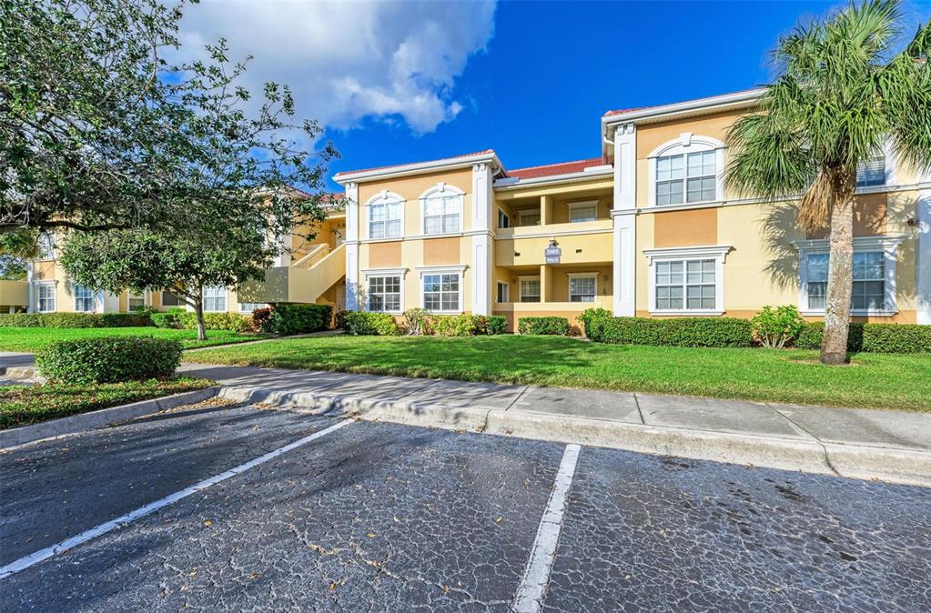 A multi-story apartment building with yellow stucco walls, white trim, and a parking lot — 3005 CHIANTI COURT UNIT 103, SARASOTA, FL