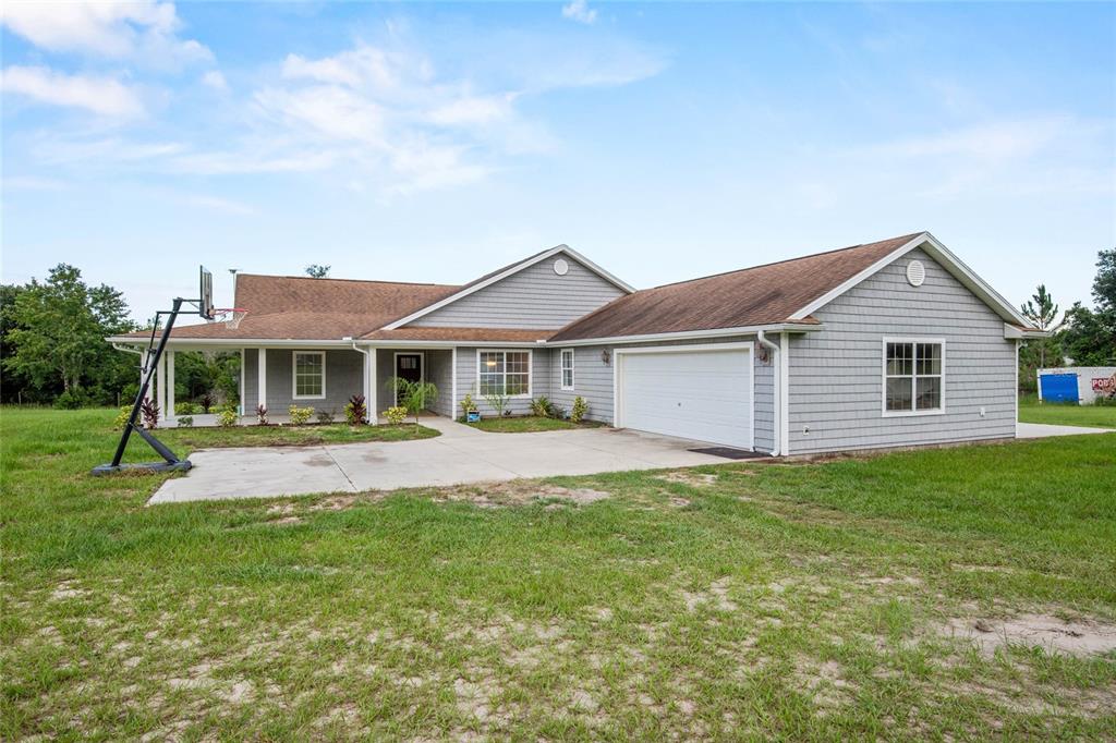 A single-story gray house with a two-car garage and a basketball hoop on the driveway — 41636 OUTLAW LANE, WEIRSDALE, FL
