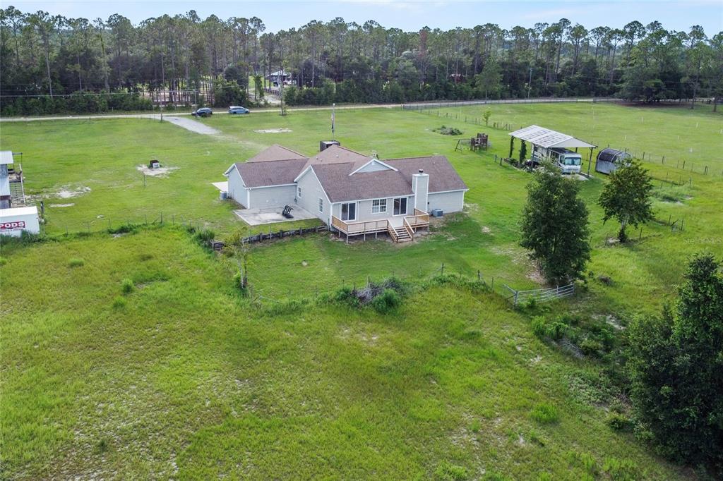 An aerial view shows a single-story house with a wooden deck on a large grassy lot — 41636 OUTLAW LANE, WEIRSDALE, FL