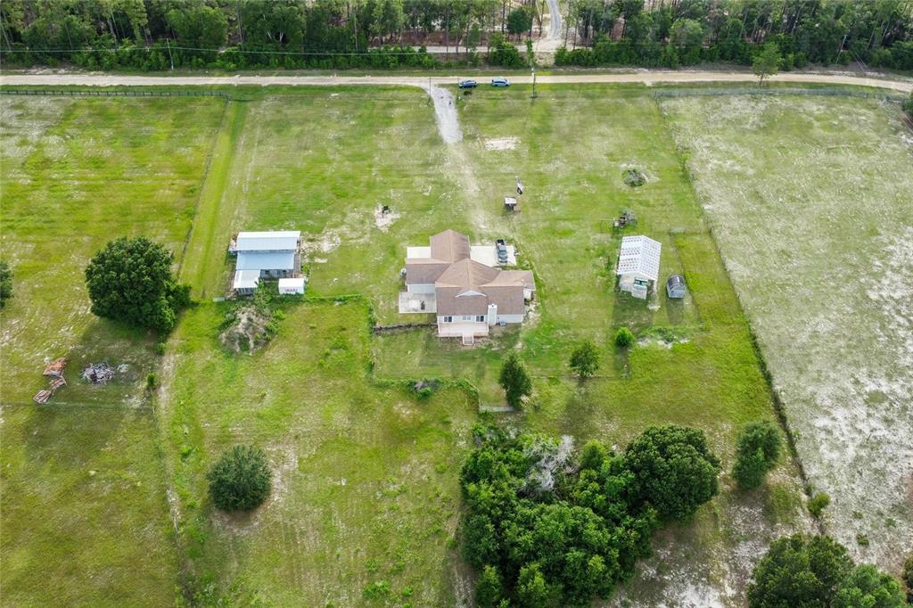 An aerial view shows a house with two outbuildings on a large, grassy rural lot — 41636 OUTLAW LANE, WEIRSDALE, FL