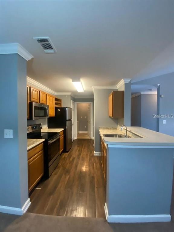 A kitchen with wood cabinets, stainless steel appliances, and a breakfast bar — 18489 BRIDLE CLUB DRIVE UNIT 184k, TAMPA, FL