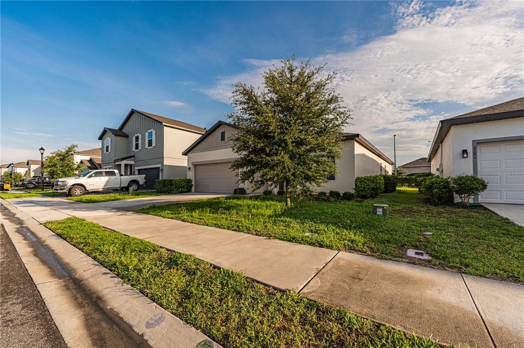 A street-level view of two suburban houses with driveways and a front yard tree — 2154 DERWENT DRIVE, DAVENPORT, FL