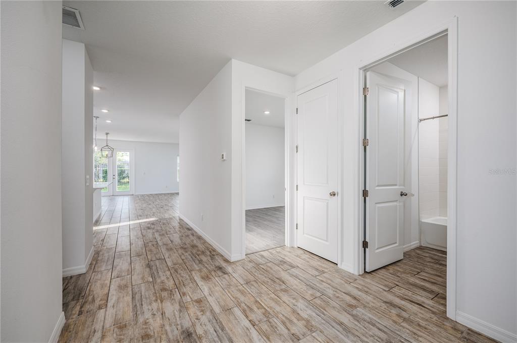 A hallway with wood-look tile flooring leads to an open living area and two doorways — 2154 DERWENT DRIVE, DAVENPORT, FL