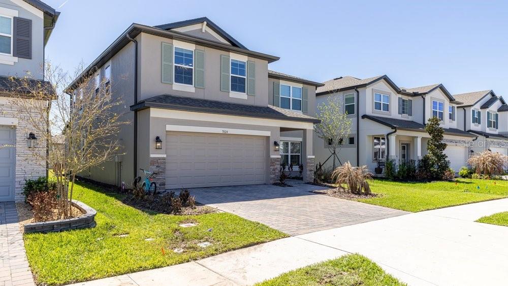 A two-story suburban house with a gray stucco exterior, a two-car garage, and a driveway — 7824 NOTCHED PINE BEND, WESLEY CHAPEL, FL