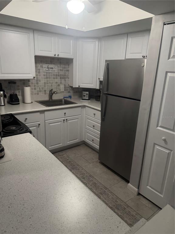 A kitchen features white cabinets, stainless steel appliances, a tiled backsplash, and light countertops — 737 MIDWAY DRIVE UNIT B, OCALA, FL