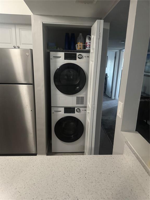 A stacked washer and dryer unit is located in a closet next to a refrigerator — 737 MIDWAY DRIVE UNIT B, OCALA, FL