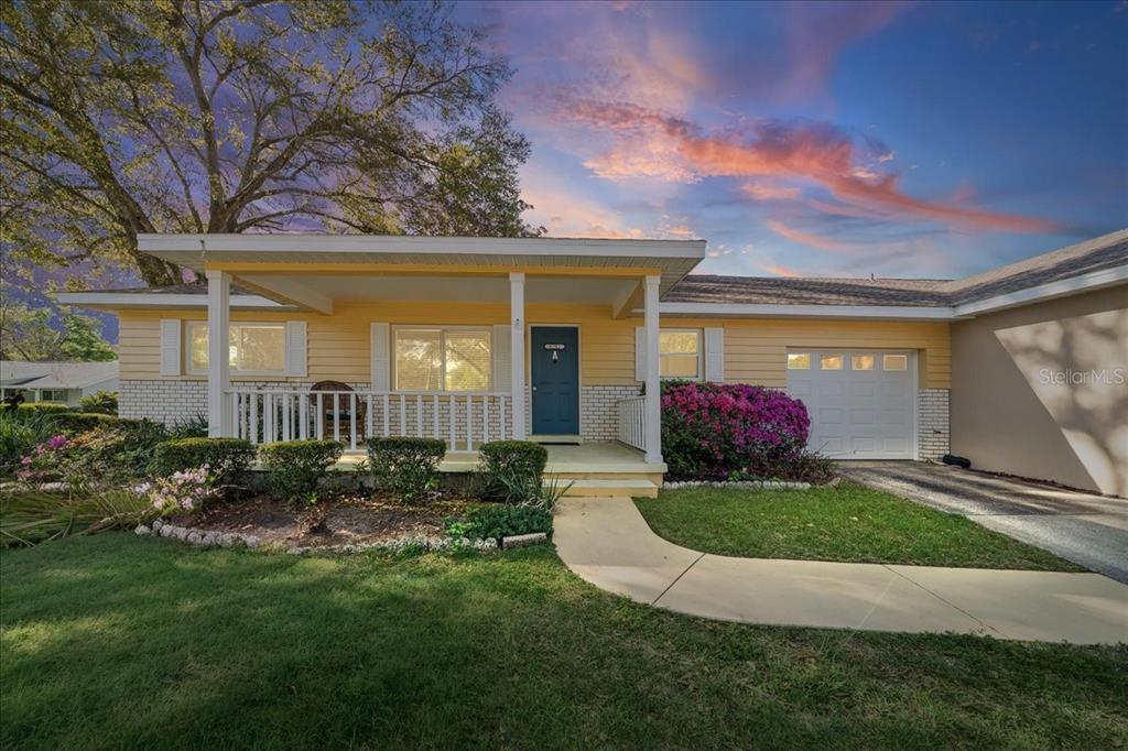 A yellow single-story house with a covered front porch, white railings, and an attached garage — 8702 SW 94TH STREET UNIT A, OCALA, FL