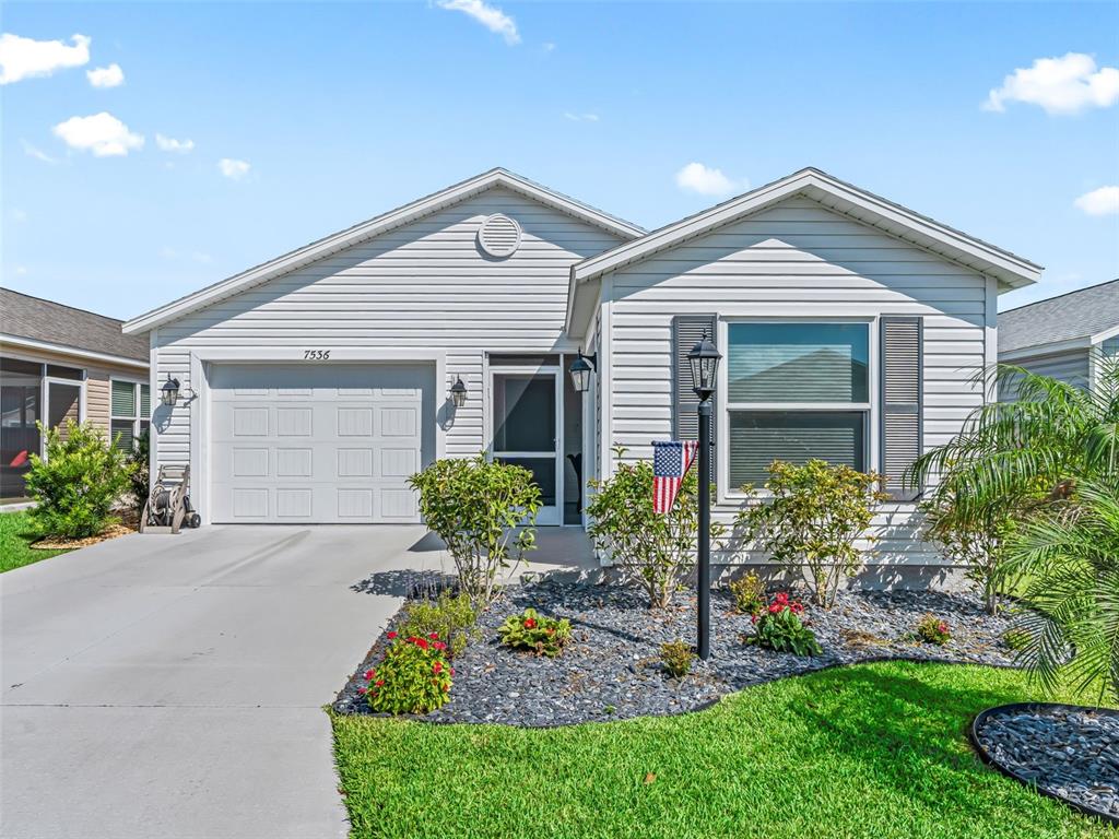 A single-story house with white vinyl siding, a one-car garage, and a landscaped front yard — 7536 KUENHER COURT, THE VILLAGES, FL