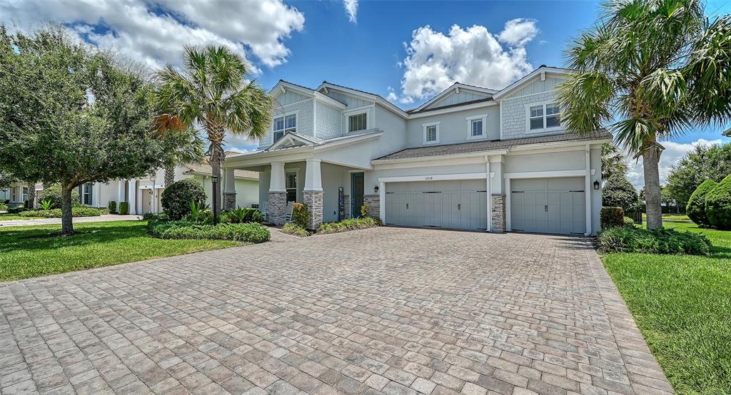 A two-story house with a paved driveway, a three-car garage, and palm trees — 12318 BLUE HILL TRAIL, BRADENTON, FL
