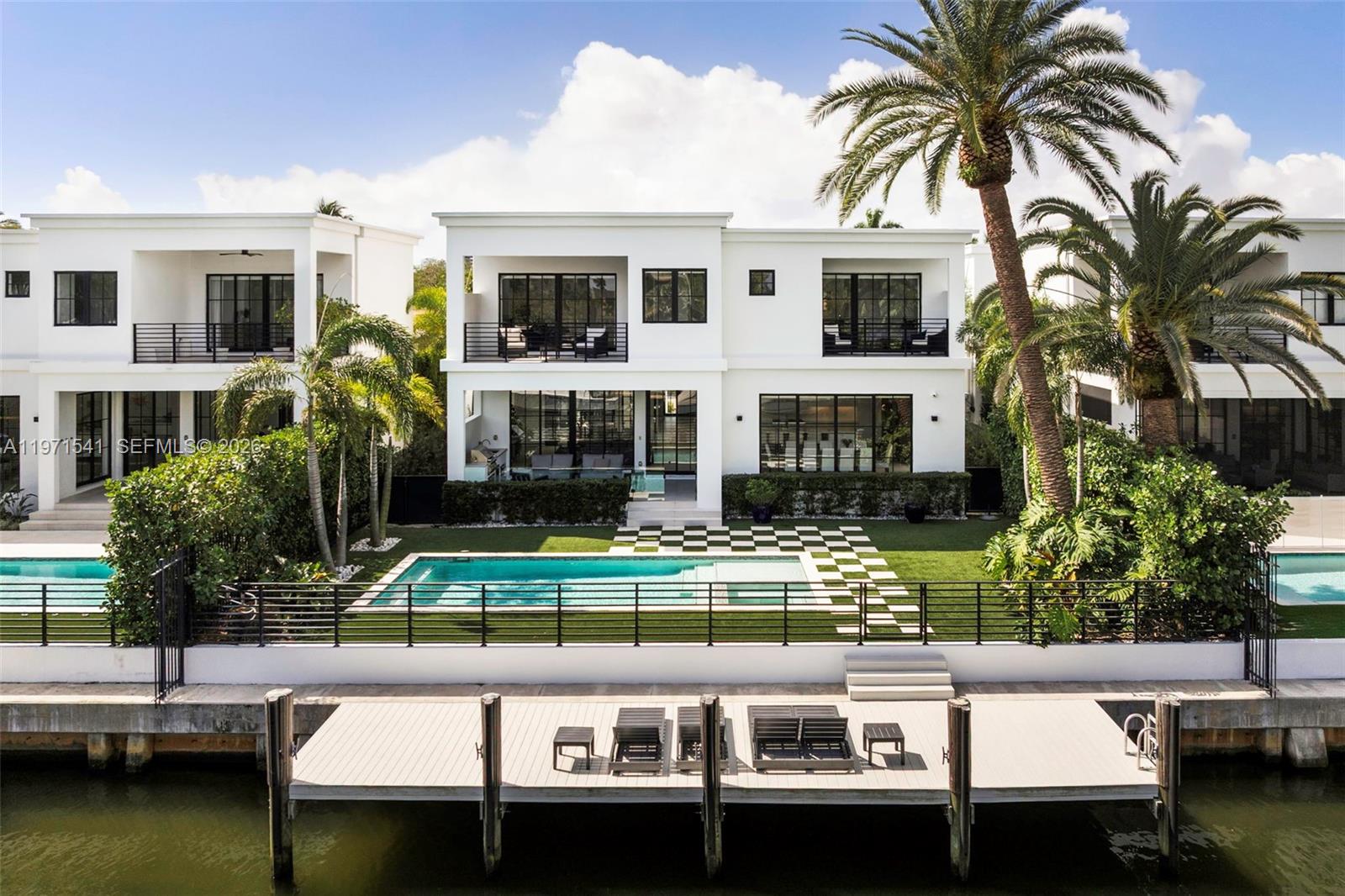 An aerial view of a modern white house with a pool, lawn, and private dock — 885 NE 76th St, Miami FL 33138, MIAMI, FL