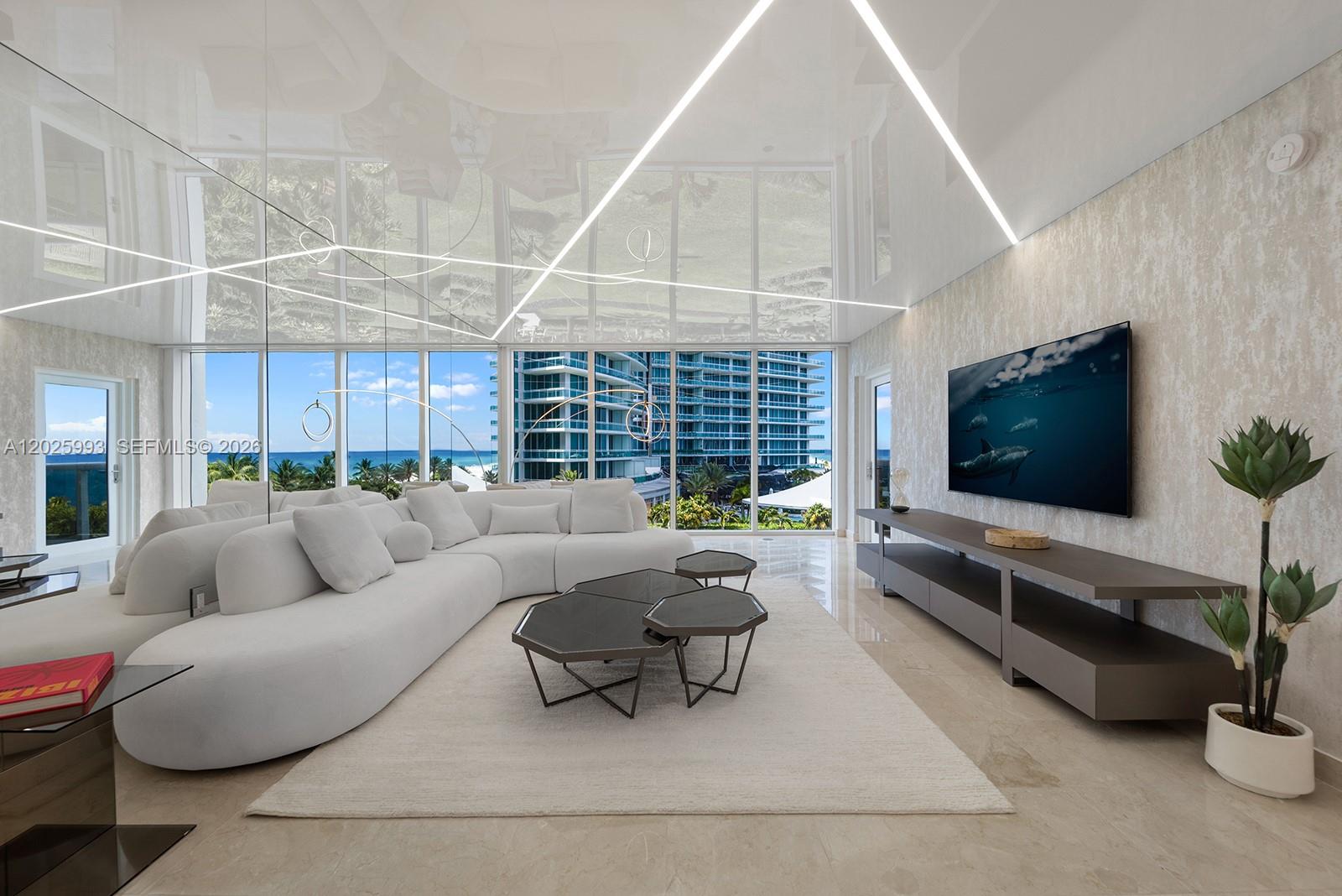 A modern living room features a white curved sofa, geometric coffee tables, and floor-to-ceiling windows — 10275 Collins Ave # 507, Bal Harbour FL 33154, BAL HARBOUR, FL