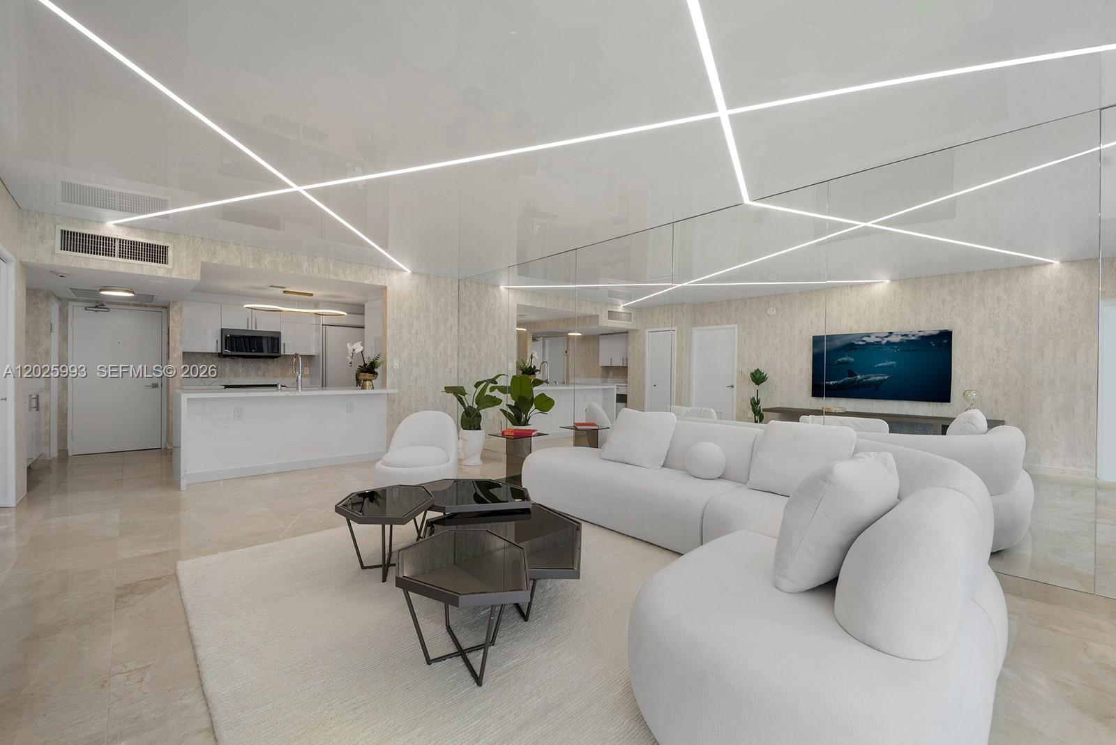 A modern living room features a white sectional sofa, geometric coffee tables, and mirrored walls — 10275 Collins Ave # 507, Bal Harbour FL 33154, BAL HARBOUR, FL