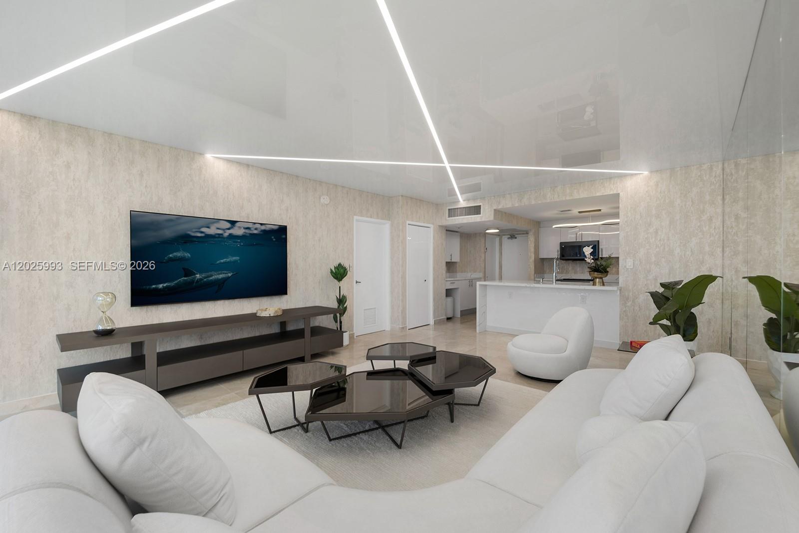 A modern living room features a white sectional, geometric coffee tables, and linear ceiling lighting — 10275 Collins Ave # 507, Bal Harbour FL 33154, BAL HARBOUR, FL