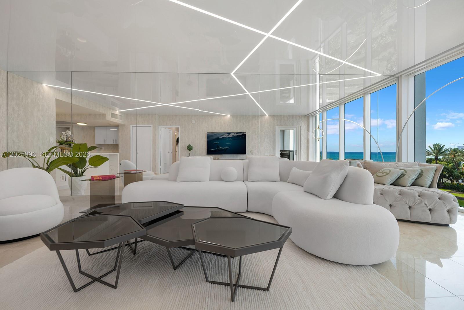 A modern living room features a white sectional sofa, geometric coffee tables, and mirrored ceilings — 10275 Collins Ave # 507, Bal Harbour FL 33154, BAL HARBOUR, FL