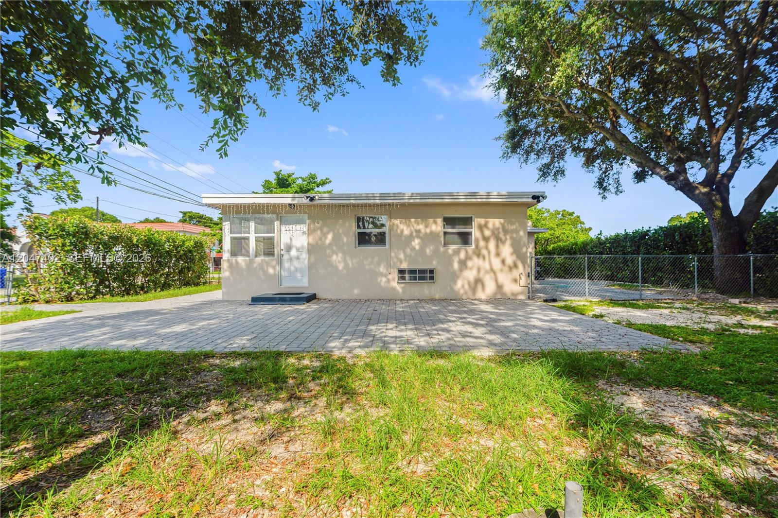 The exterior of a single-story house features a paved patio, a white door, and windows — 5800 Taylor St # 2, Hollywood FL 33021, HOLLYWOOD, FL