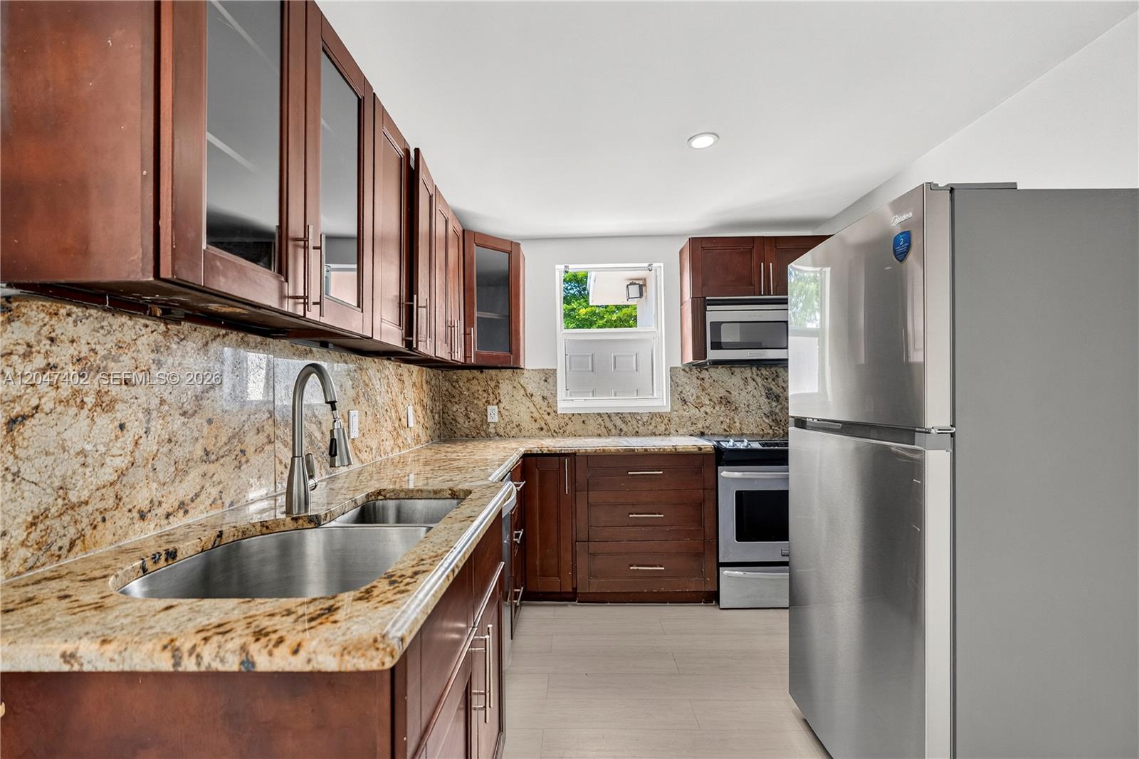 A kitchen features dark wood cabinets, granite countertops, stainless steel appliances, and a double sink — 5800 Taylor St # 2, Hollywood FL 33021, HOLLYWOOD, FL