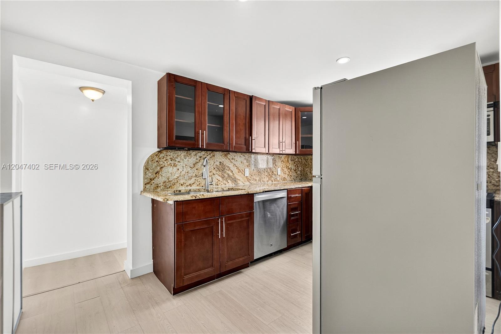 A kitchen features dark wood cabinets, granite countertops, and stainless steel appliances — 5800 Taylor St # 2, Hollywood FL 33021, HOLLYWOOD, FL