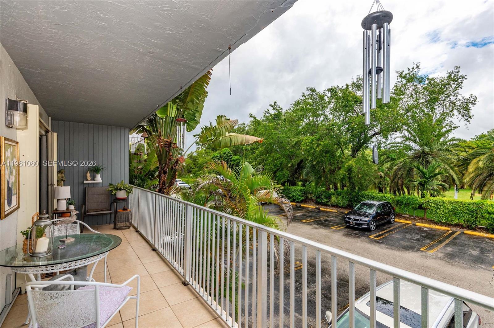A balcony with tile flooring, white metal railings, patio furniture, and a view of parking — 7403 SW 82nd St # 212N, Miami FL 33143, MIAMI, FL
