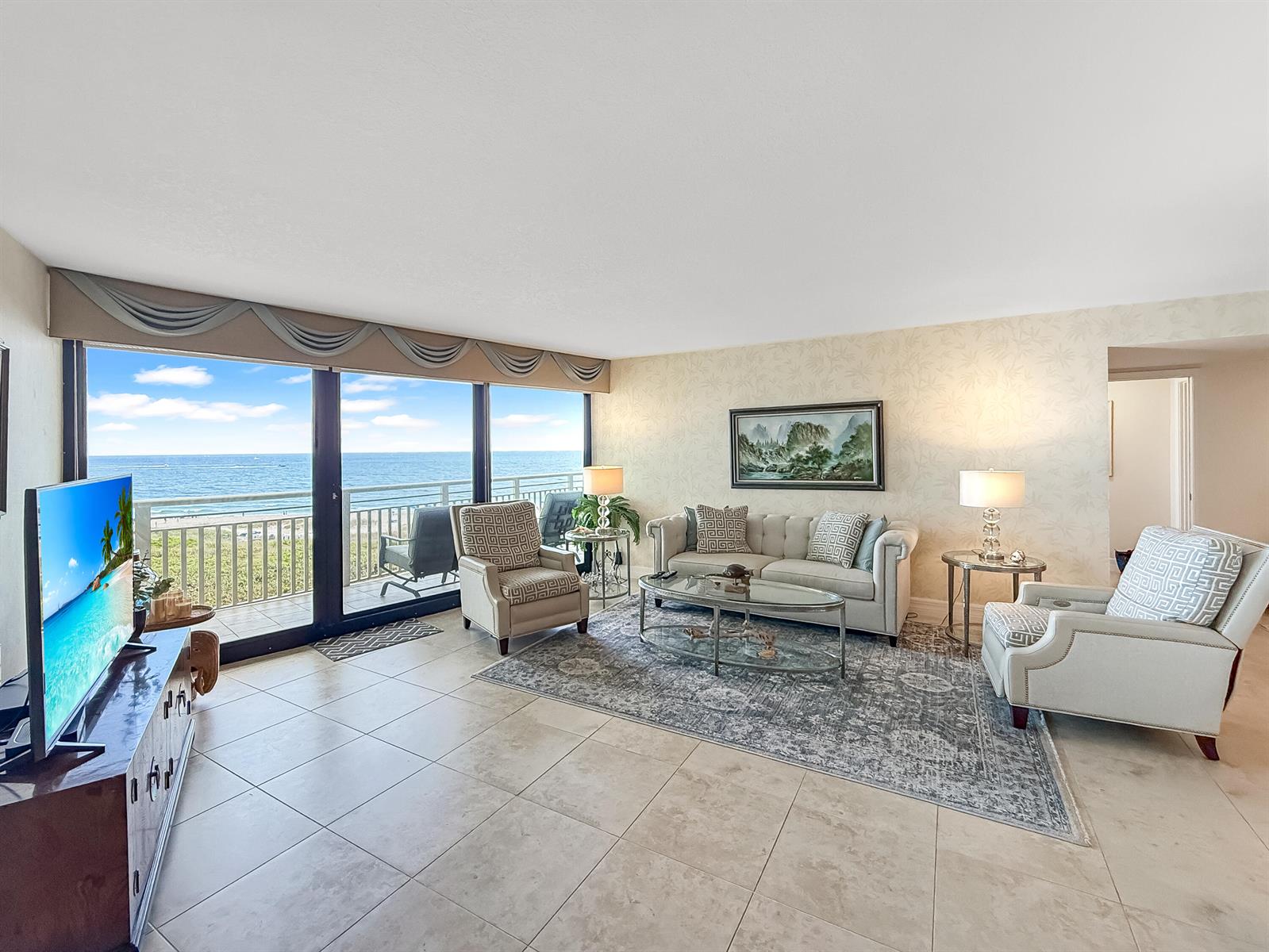 A living room features tile floors, a sofa, armchairs, and a balcony overlooking the ocean — 3000 N Ocean Drive, Singer Island FL 33404, SINGER ISLAND, FL
