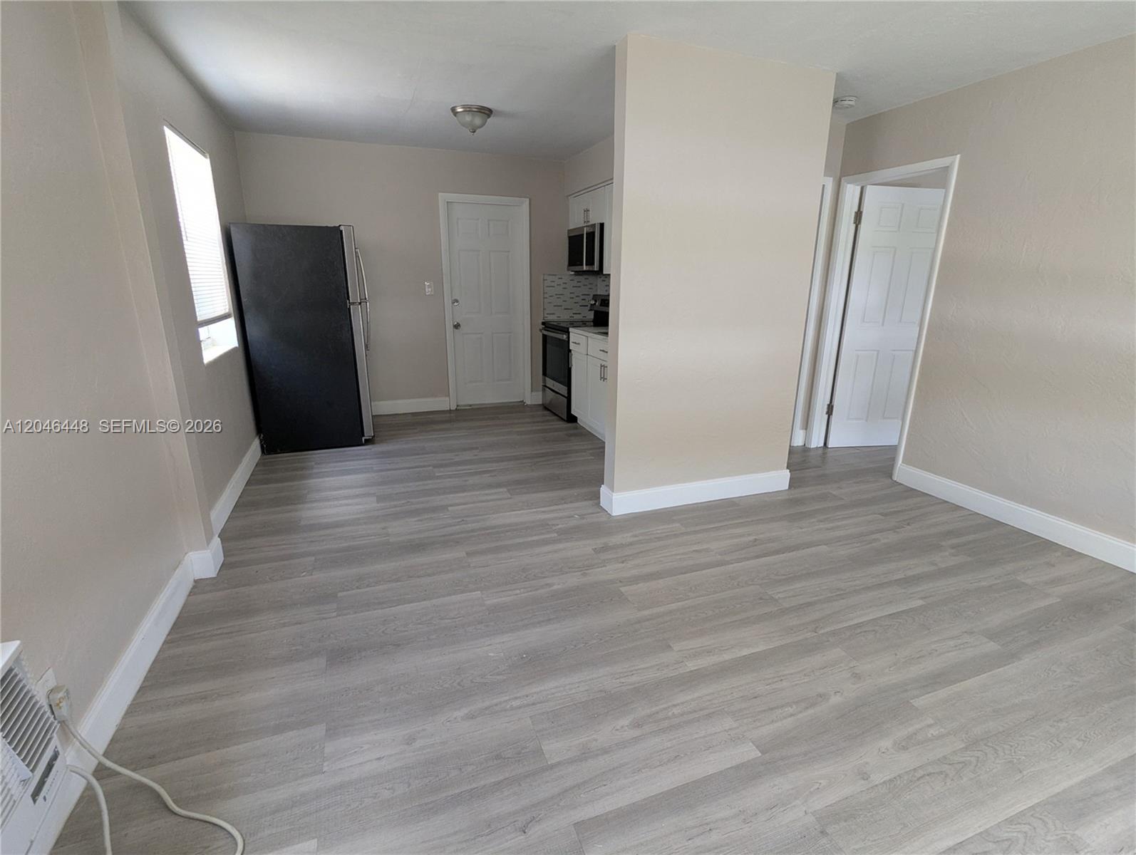 A kitchen area with light wood-look flooring, a black refrigerator, and white cabinets — 2300 Douglas St # 1, Hollywood FL 33020, HOLLYWOOD, FL