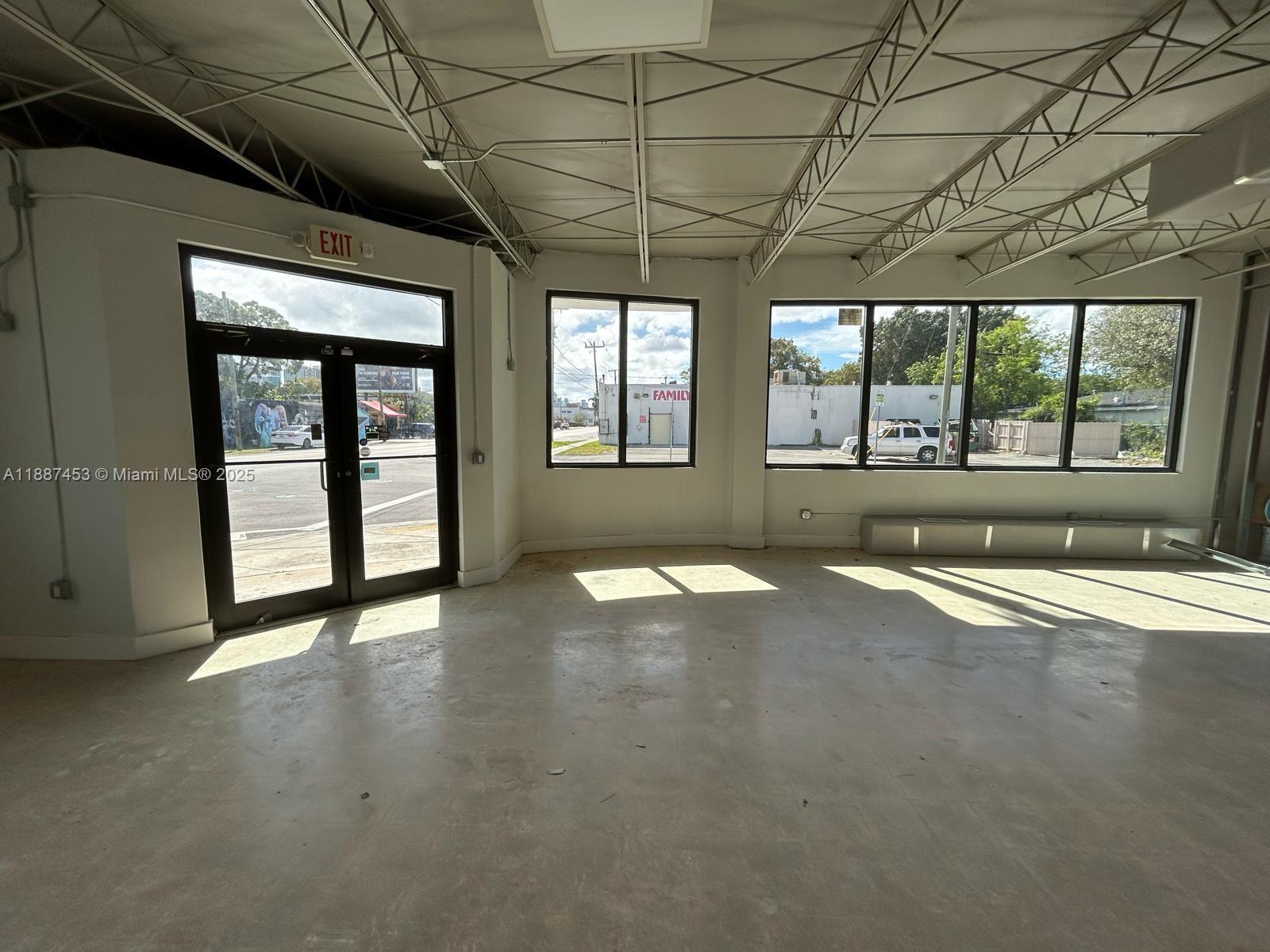 An empty commercial space with concrete floors, exposed ceiling trusses, and large windows — 4200 NW 2nd Ave, Miami FL 33127, MIAMI, FL