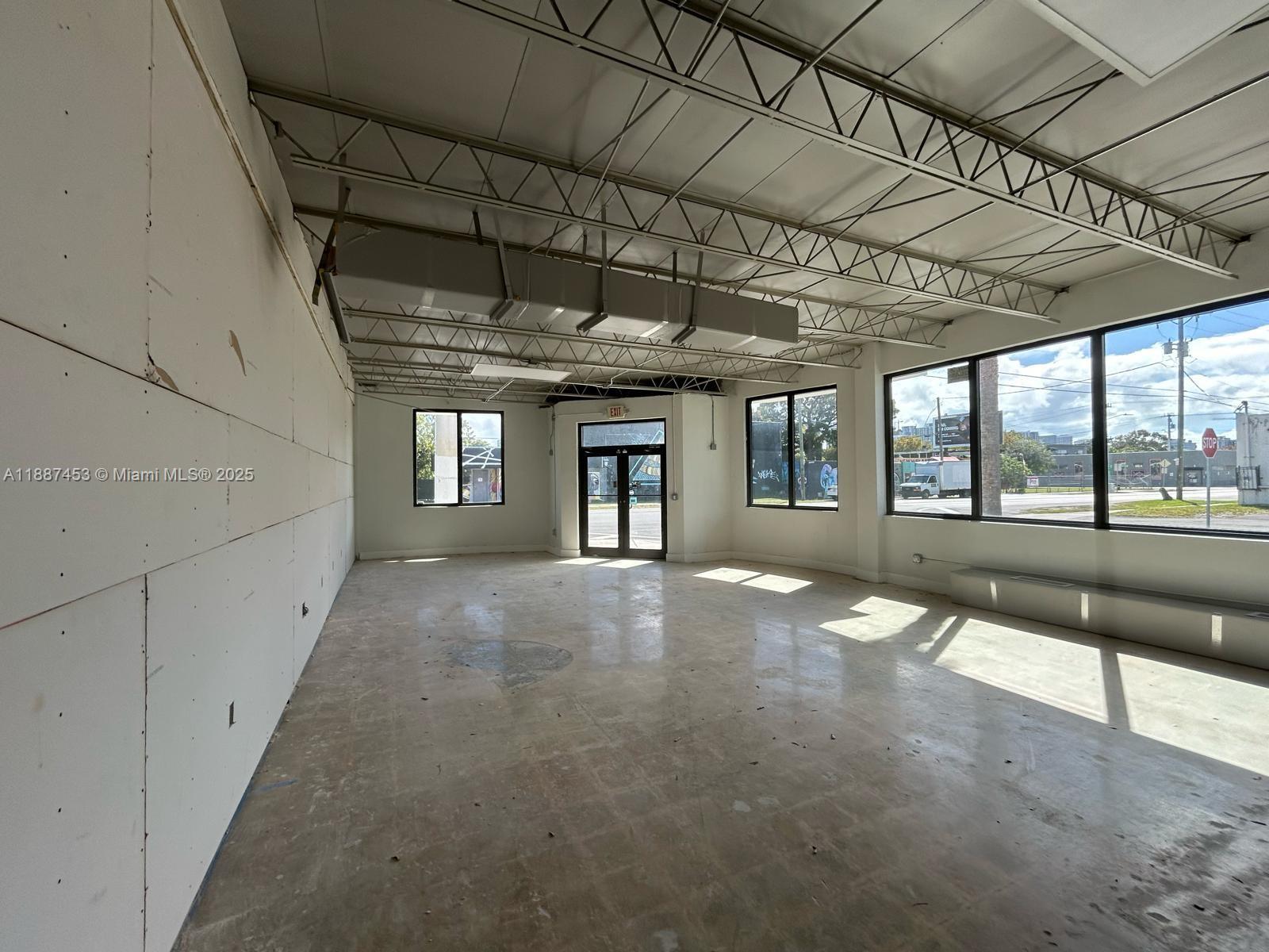 An empty commercial space features exposed ceiling trusses, concrete floors, and large windows — 4200 NW 2nd Ave, Miami FL 33127, MIAMI, FL
