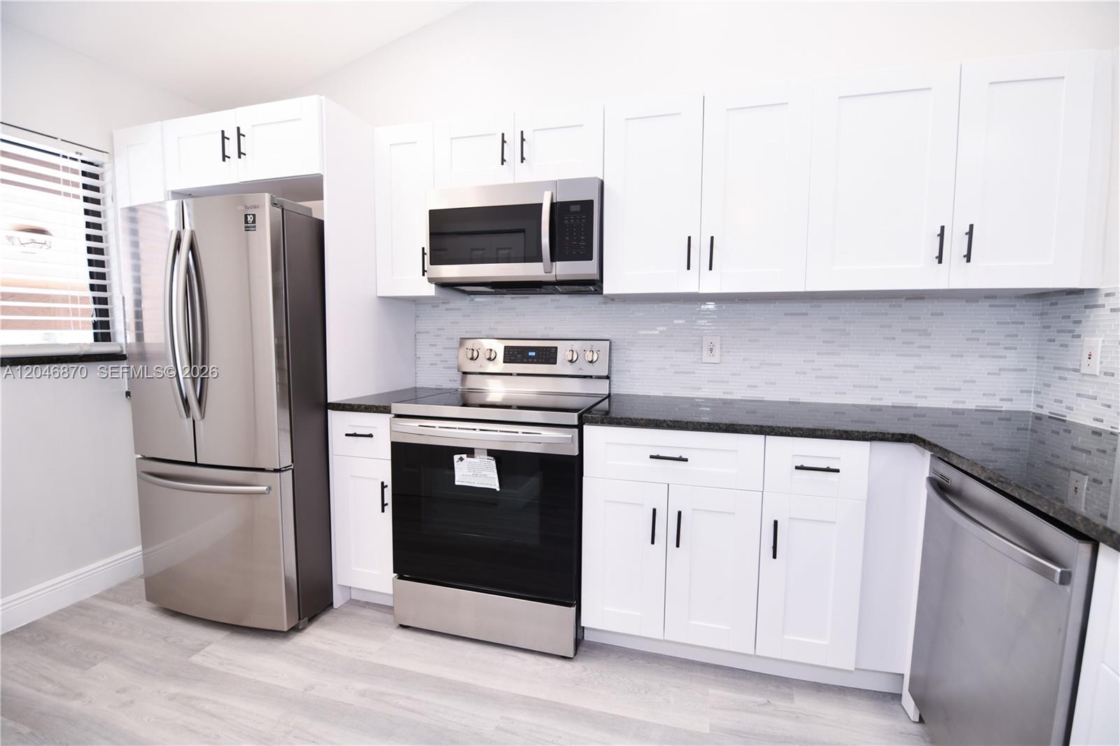 A kitchen features white shaker cabinets, stainless steel appliances, and a dark granite countertop — 2315 SW 22nd Ave # 2020, Delray Beach FL 33445, DELRAY BEACH, FL