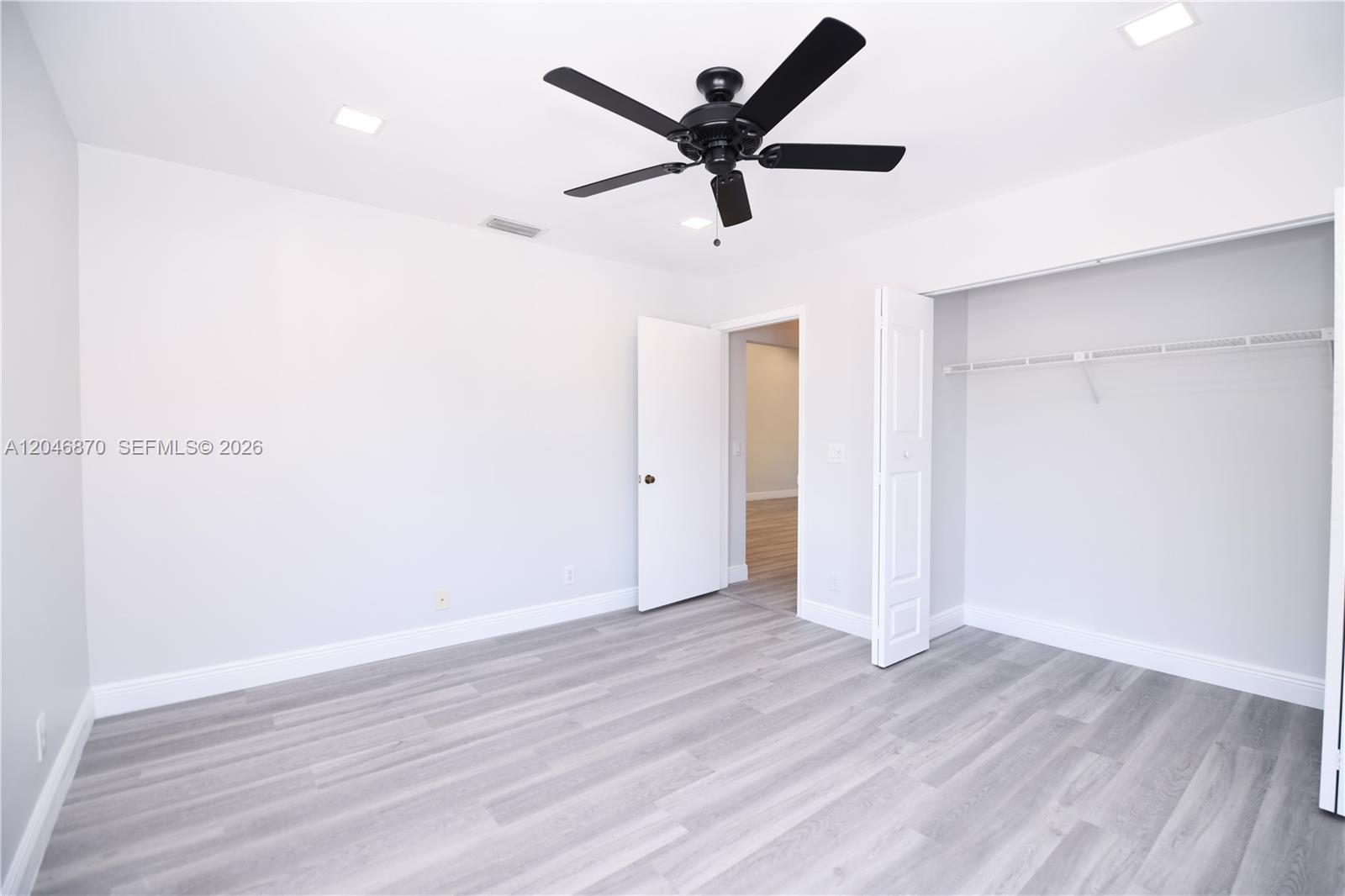 This bedroom features light gray wood-look flooring, white walls, a ceiling fan, and a closet — 2315 SW 22nd Ave # 2020, Delray Beach FL 33445, DELRAY BEACH, FL
