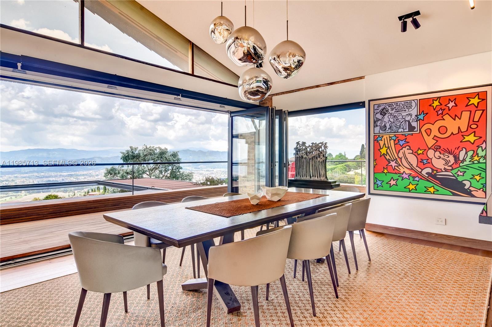 A modern dining room features a large wooden table, pendant lights, and expansive mountain views — 2 Vía Chía Condominio Sindamanoy, FL, FL