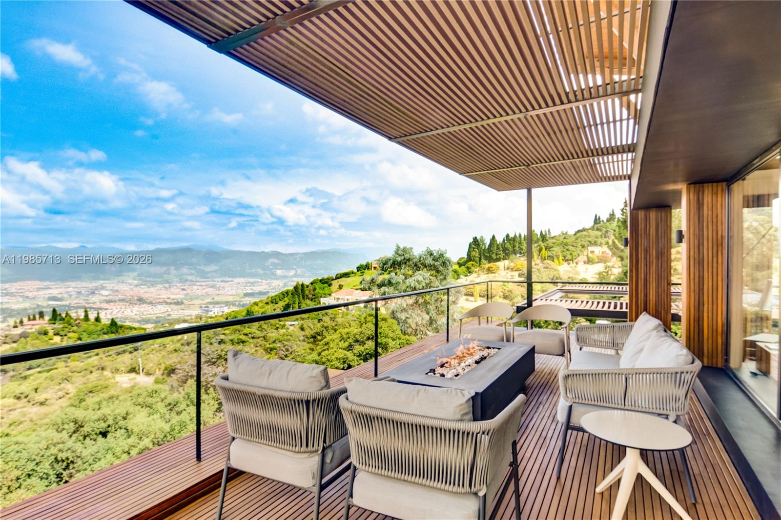 A modern outdoor balcony features a fire pit, lounge seating, and panoramic mountain views — 2 Vía Chía Condominio Sindamanoy, FL, FL