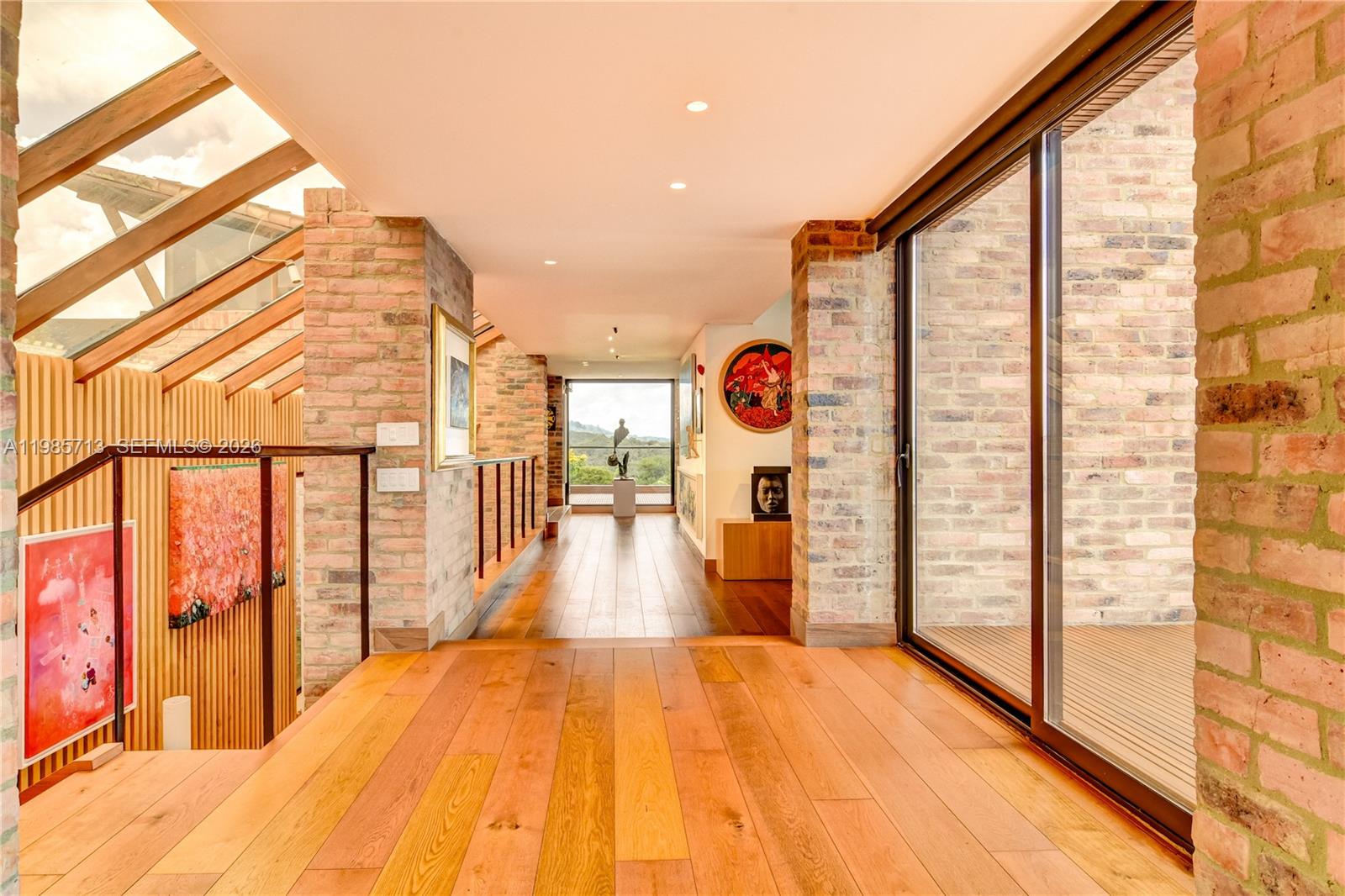 A hallway with wooden floors, brick walls, and a glass-enclosed view of the outdoors — 2 Vía Chía Condominio Sindamanoy, FL, FL