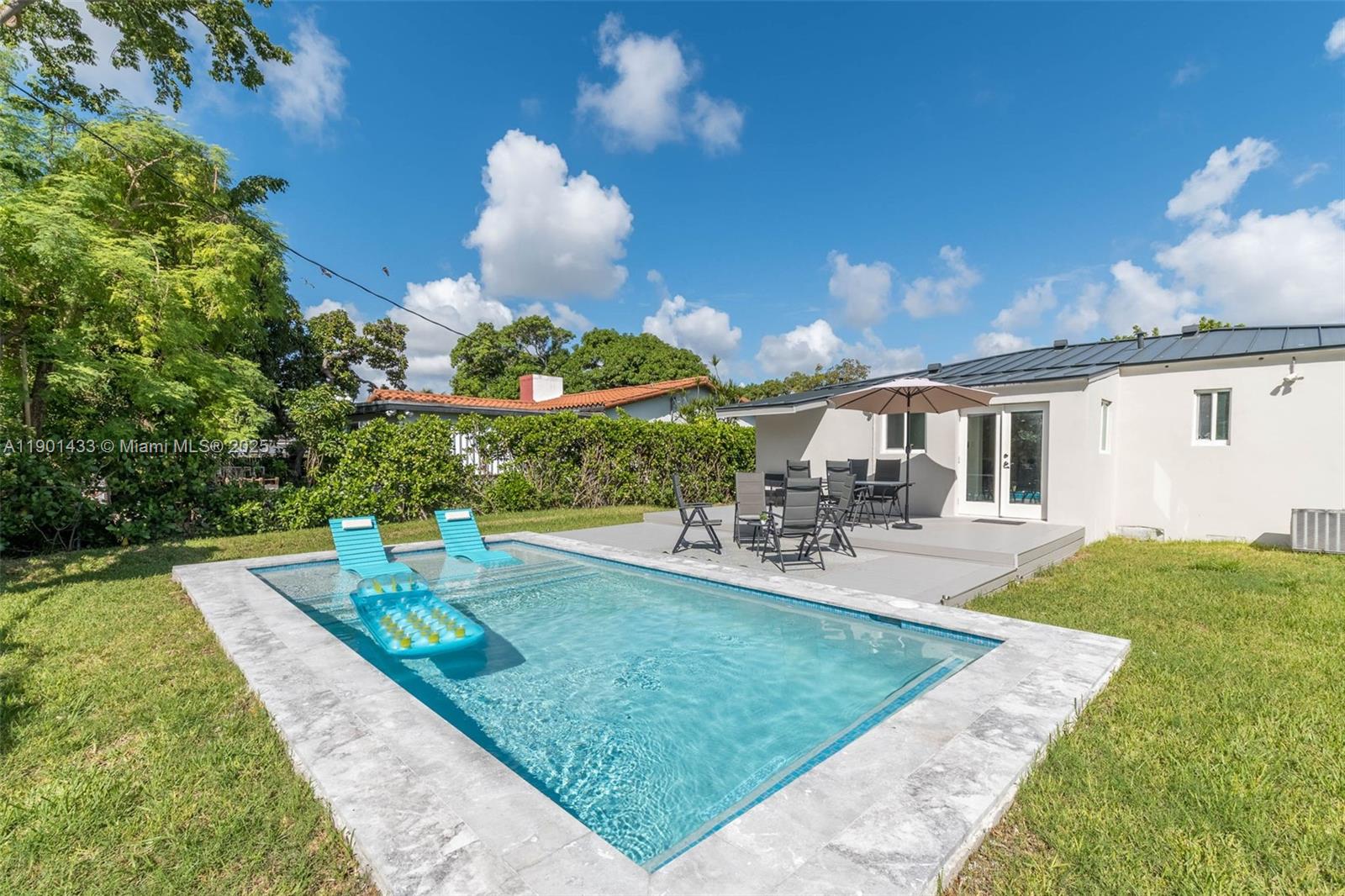 A backyard features a rectangular swimming pool with lounge chairs and a patio dining area — 260 NE 46th St, Miami FL 33137, MIAMI, FL