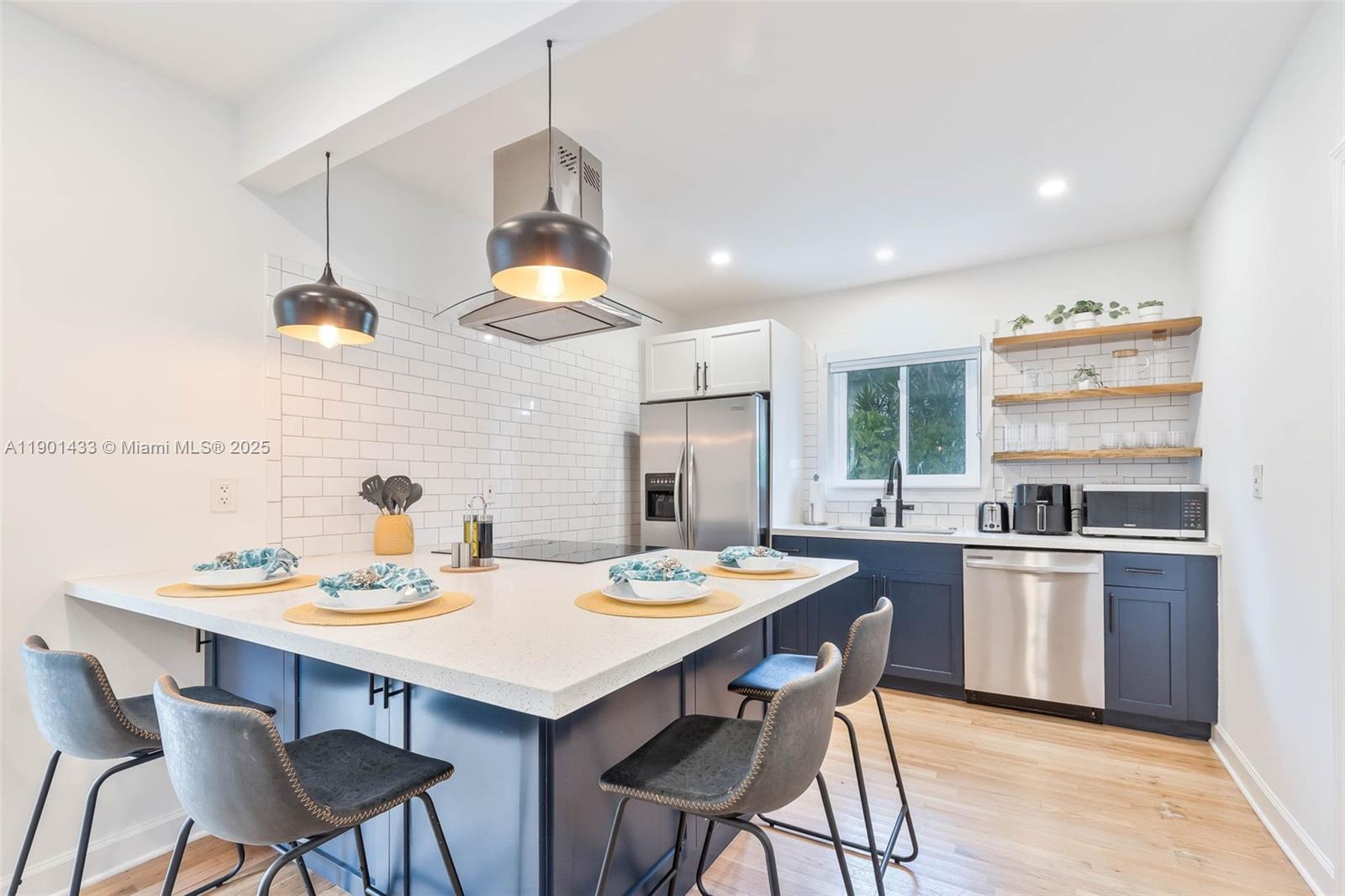 A kitchen features a large island, dark blue cabinetry, white subway tile, and open shelving — 260 NE 46th St, Miami FL 33137, MIAMI, FL