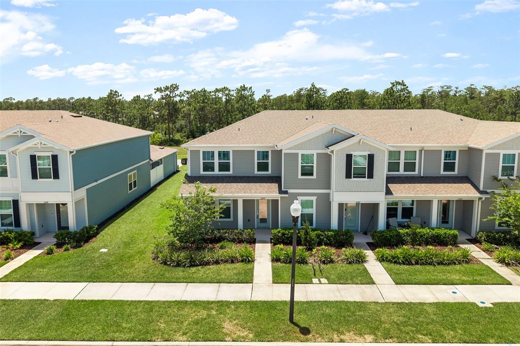 An exterior view of a multi-unit townhouse complex with gray siding and a shingled roof — 5592 PINELAND RUN, ORLANDO, FL