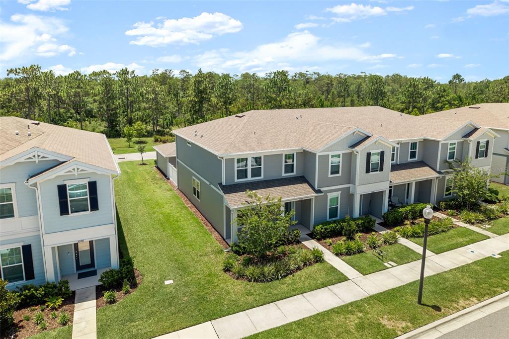 An exterior view of two-story townhomes with light blue and gray siding and shingled roofs — 5592 PINELAND RUN, ORLANDO, FL