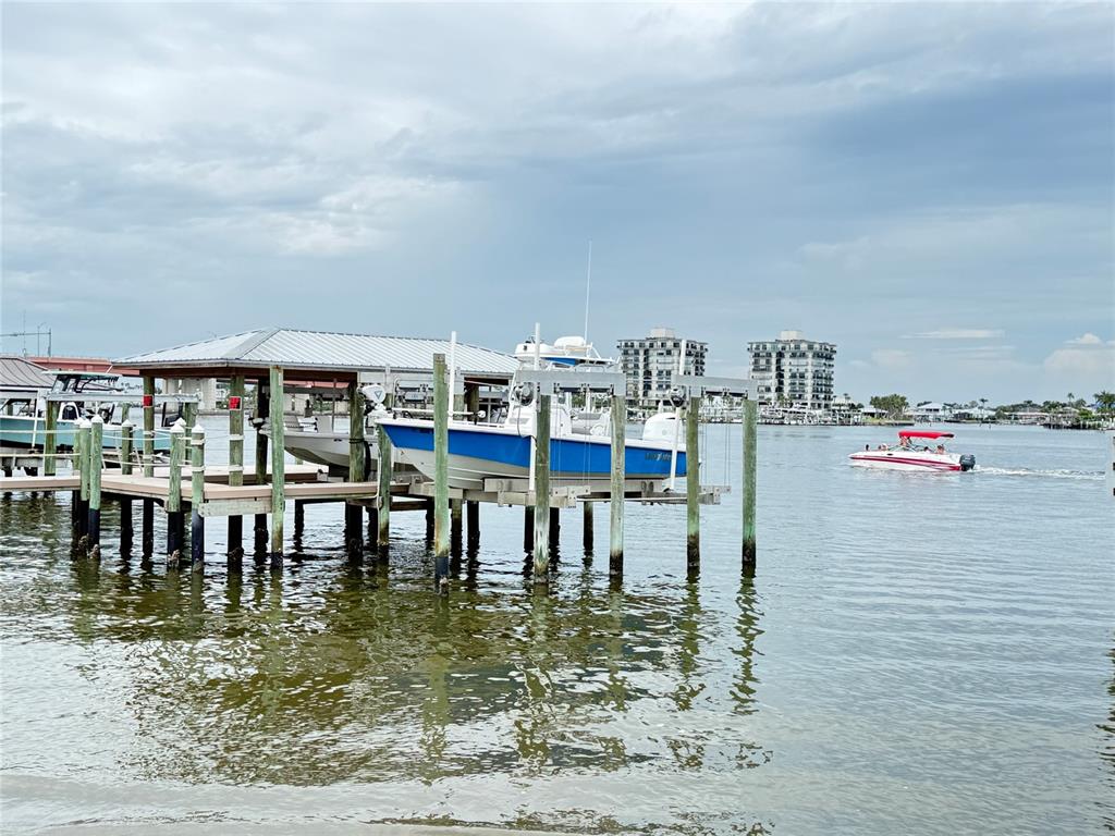 A blue and white motorboat sits on a lift at a wooden dock near water — 101 DUE EAST STREET, NEW SMYRNA BEACH, FL